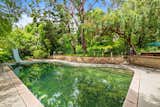 Outdoor, Back Yard, Trees, Gardens, Flowers, Shrubs, Large Pools, Tubs, Shower, and Walkways Expansive Pool Set Beneath Towering Trees  Photo 12 of 13 in French Normandy Revival Estate In Coveted Enclave of Beverly Hills Lists for $8.5M by Beyond Shelter
