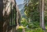 A darkened exterior palette allows the home to recede into the surrounding forest, echoing the quiet elegance of its alpine setting.