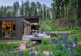 The long shed roof lifts toward the sound of the creek, sheltering a generous covered deck that invites year-round connection to nature.