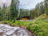 The long shed roof lifts toward the sound of the creek, sheltering a generous covered deck that invites year-round connection to nature.