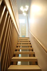 Open risers at the stair allow for light from the skylight and suspended fixture to filter through.