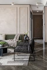 The muted modern sleek living room with grey marble flooring and a curved emerald sofa as the highlight and simple black and white arm chair by its side, walls with Victorian panelling finished is texture and black wooden cornice running on all border add character to the space . On the left is simple elegant mandir with triangle fluting and on the right is an oblong Michael Angelo Dining table with bronze metal legs and black domed shaped pendant light.Globe lights on ceiling add to the drama and grandness of room.
Sofa ,Dinning Table , Dinning Chair - Custom Made
Carpet - Jaipur Rug
Center table- Eter 
Dinning Light - Shailesh Rajput
Arm Chair - The Pure Concept Home
