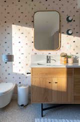 graphic wallpaper in bathroom with mirror over sink in cabinet