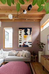 Benjamin Moore's Barberry paint accents a wall in the living room, which it lit by a chandelier by Andrew Neyer. The ottoman is by Muuto.