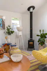 The original wood-burning stove warms the home, now in front of Zellige wainscoting and a floor lamp by UM Project.
