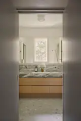 The custom primary bathroom's vanity was fabricated by NY Fine Interiors with a marble countertop that color-matches the terrazzo tile flooring.