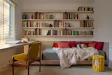 Custom shelves by Architecture in Formation, built by Off the Grid Solutions line the office with its bespoke daybed, a cozy spot for architect Matthew Bremer's rescued greyhound, Saluki.  A Corn Cob table by Vibey XO from Coming Soon NYC stands atop the Tibetan rug from Tai Ping NYC.