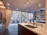 Kitchen, Undermount Sink, Recessed Lighting, Refrigerator, Wall Oven, Wood Cabinet, Ceiling Lighting, and Porcelain Tile Floor View from kitchen sink looking into custom millwork shelving with opening above to second floor.  Photo 3 of 11 in Black in Back House by Nadia Cannataro
