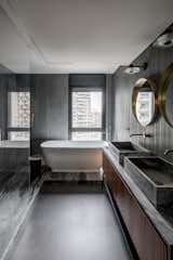Bath Room, Freestanding Tub, Vessel Sink, Porcelain Tile Floor, Wall Lighting, Porcelain Tile Wall, and Marble Counter Bathroom   Photo 17 of 22 in The Black Silhouette Apartment by ORKO STUDIO