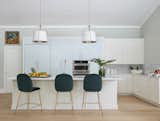 Velvet Modway stools stand below Ballard Design’s Adelaide pendants in the kitchen.  Christopher Farr Cloth’s Africana wallpaper complements the marble backsplash and countertops from Ceramic Matrix.