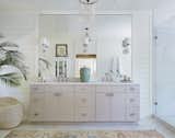 A custom white master barroom with a light pink hued vanity, and topped with antiques.