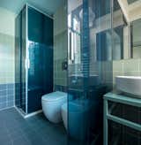 The colours of the transparent tempered glass sliding doors of the dressing room and shower reflect the aquamarine green of the fixtures and vertical wall coverings.
