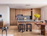 The kitchen features warm-walnut-clad Fisher Paykel appliances, an earth-toned Japanese tile backsplash, and Caesarstone countertops for a bright finish.