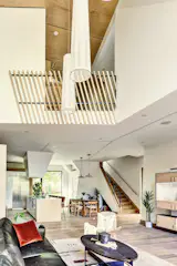 view from living room to dining and kitchen- white oak cabinetry, white oak wide plank floor, black metal enclosures and railing, white Silestone countertop.