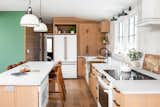 Kitchen, Refrigerator, Engineered Quartz Counter, Wood Cabinet, Wall Lighting, Cooktops, Dishwasher, Medium Hardwood Floor, Undermount Sink, Pendant Lighting, Ceramic Tile Backsplashe, Wall Oven, Microwave, Range Hood, and Recessed Lighting Riverside Getaway Airbnb kitchen  Photo 8 of 19 in Getaway Motor Café and Riverside Getaway Airbnb by Studio Grey