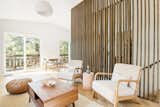Open-concept living space with wooden slats, large sliding glass doors with natural sunlight. 