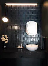 A gleamingly dark powder room with ornate mosaic tiles that are tactile and locally made.