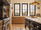 Range wall featuring artisanal black glazed tile that reflects natural light. Windows along the sink wall allow the view out to the water. 