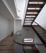 The zig-zag staircase turns corners with the bending glass handrails to match the curved skylight 