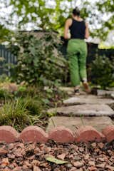 Outdoor, Shrubs, Back Yard, Flowers, Trees, Wood Fences, Wall, Grass, Garden, Walkways, and Gardens Upcycled concrete pavers create a path between the raingardens to the storage shed and compost bin.  Photo 13 of 21 in La Croix House by Jennifer Martin