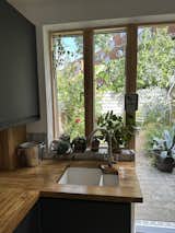 Kitchen, Wood Counter, Laminate Cabinet, Ceramic Tile Backsplashe, Limestone Floor, Undermount Sink, and Ceiling Lighting View through the kitchen window  Photo 5 of 11 in Kentish Town Oasis by Sam Stork