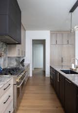 Kitchen featuring rift sawn white oak cabinets in a natural stain on the perimeter, ebony on the island. Italian marble countertops grace the full backsplash as well as a double waterfall detail on both island ends.  