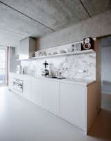 Kitchen, Drop In Sink, Stone Slab Backsplashe, White Cabinet, Marble Counter, and Concrete Floor Stunning kitchen with marble slab countertop and backsplash.  Photo 2 of 12 in Senso for Sitzler Berlin by David Bols