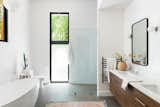 Primary suite bathroom showing custom vanity, a zero entry shower and floating tub complete with wooded views.