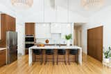 Kitchen view showing custom two toned walnut and white cabinetry and island with waterfall end panels. 