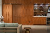 Living Room, Concrete Floor, and Accent Lighting Floor to ceiling walnut paneled wall with mini bar.  Photo 1 of 11 in The Modernist Pool House by Wayne Truax