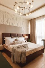 The bedroom with the asymmetrical design of the art-deco wall, the fluted panel and the tan leather headboard. The entire space is finished with lime plastered walls adding to the visual comfort. 