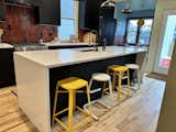 Kitchen, Drop In Sink, Ceiling Lighting, Marble Counter, Light Hardwood Floor, Laminate Cabinet, Cooktops, and Refrigerator Vintage sourced stools under the bar.  Photo 5 of 11 in The vintage modern mix house by Sasha Shver