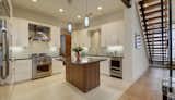 Kitchen, Wall Oven, Refrigerator, Ceiling Lighting, Range Hood, Range, White Cabinet, Medium Hardwood Floor, Ceramic Tile Backsplashe, Drop In Sink, Pendant Lighting, and Recessed Lighting  Photo 5 of 13 in Infill Contemporary Home by J Christopher Architecture