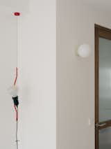 Custom-made wooden door and hallway sconce by La Quincallerie Moderne. Vertical lamp is made by Flos.