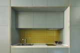 the kitchen with sage green laminated joinery, carrara marble top and yellow tiles back