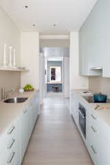 A peak at the entryway via the kitchen. Glossy cabinets meet sleek neutral countertops.