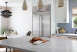 Kitchen, Pendant Lighting, Light Hardwood Floor, Ceiling Lighting, White Cabinet, Refrigerator, Quartzite Counter, and Brick Backsplashe The simplicity of the Folk Angular Cylinder Pendants pairs well with the geometric shapes of the Kokoro Chandelier by Troy Lighting.  Photo 6 of 10 in 1960's Japandi by Michelle Lisac