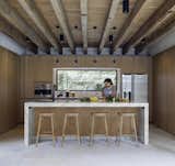 Kitchen, Wood Cabinet, Concrete Floor, Granite Counter, Ceiling Lighting, Concrete Backsplashe, Drop In Sink, Wall Oven, Refrigerator, Microwave, Dishwasher, and Wine Cooler  Photo 14 of 19 in Noah House by Cadaval Estudio