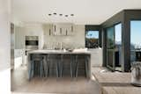 Kitchen, Pendant Lighting, Light Hardwood Floor, Marble Backsplashe, Range Hood, Range, Marble Counter, Undermount Sink, Ceiling Lighting, White Cabinet, and Wall Oven  Photo 7 of 17 in Sunridge House by Conrad Asturi Studios