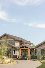 Rustic lodge vibes, covered front entry, exterior design. Reclaimed wood siding, corrugated metal roofs. Sustainable, natural materials, biophilic design. Skyway bridge over waterfall, luxury water feature.