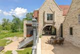 Castle house. Stone home exterior. Outdoor dining and living area. Exterior staircase. Stone arches and beautiful exterior design detail. Custom railing and lampposts.