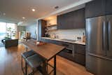 Kitchen, Ceiling Lighting, Wood Cabinet, Refrigerator, Dishwasher, Medium Hardwood Floor, Stone Tile Backsplashe, Microwave, Stone Counter, and Drop In Sink Full Kitchen Entry  Photo 2 of 12 in Natiivo Austin Condo by Spyglass Realty