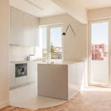 Kitchen, Ceiling Lighting, Colorful Cabinet, Refrigerator, Concrete Floor, Marble Counter, Wall Oven, Marble Backsplashe, Wall Lighting, Dishwasher, and Drop In Sink Open Kitchen   Photo 9 of 23 in Curves of Progress: A Contemporary Rehabilitation in Graça, Lisbon by blaanc