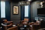 Behind a hidden door lies a speakeasy-style man cave complete with a built-in bar. Dark leather furniture and cocktail tables round out the moody and mysterious aesthetic. 