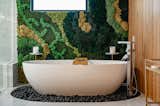 The main bathroom includes a moss wall behind a free standing bath tub, inviting the serene colors and textures of nature inside and evoking a sense of peace and tranquility to those inside. 