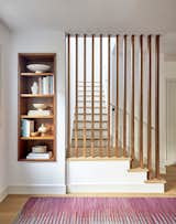 Mid-century inspired walnut screen opens up the stairs to the ground floor, adjacent to built-in book shelf 
