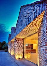 A dance of light and texture: Rear elevation bathed in a warm glow, courtesy of discreet uplighters nestled in the paving, accentuating the brick texture