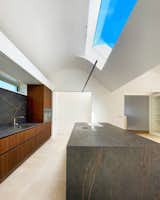 Kitchen, Porcelain Tile Floor, Undermount Sink, Marble Backsplashe, Quartzite Counter, Range, Wall Oven, Ceiling Lighting, and Wood Cabinet Large rooflights allow inhabitants to observe the ever-changing Dublin sky above  Photo 9 of 18 in Elevated Living: A new build house in Mount Merrion by David Flynn Architects Ltd