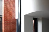 Sculpted eleganceThe curved kitchen bulkhead (containing the extract duct) forms a seamless connection with the kitchen window, elegantly contrasting the red brick pier outside. The smooth white plaster adds a touch of modernity, and the graduated light within the monochrome interior sets a refined ambiance