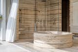 The primary bathroom is created entirely in an understated Silver Travertine on the floors, walls and even on the shower ceiling. 